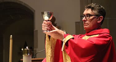 President Linnane wearing red robes and holding a goblet