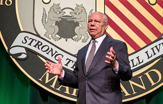 Colin Powell speaking on stage at Loyola